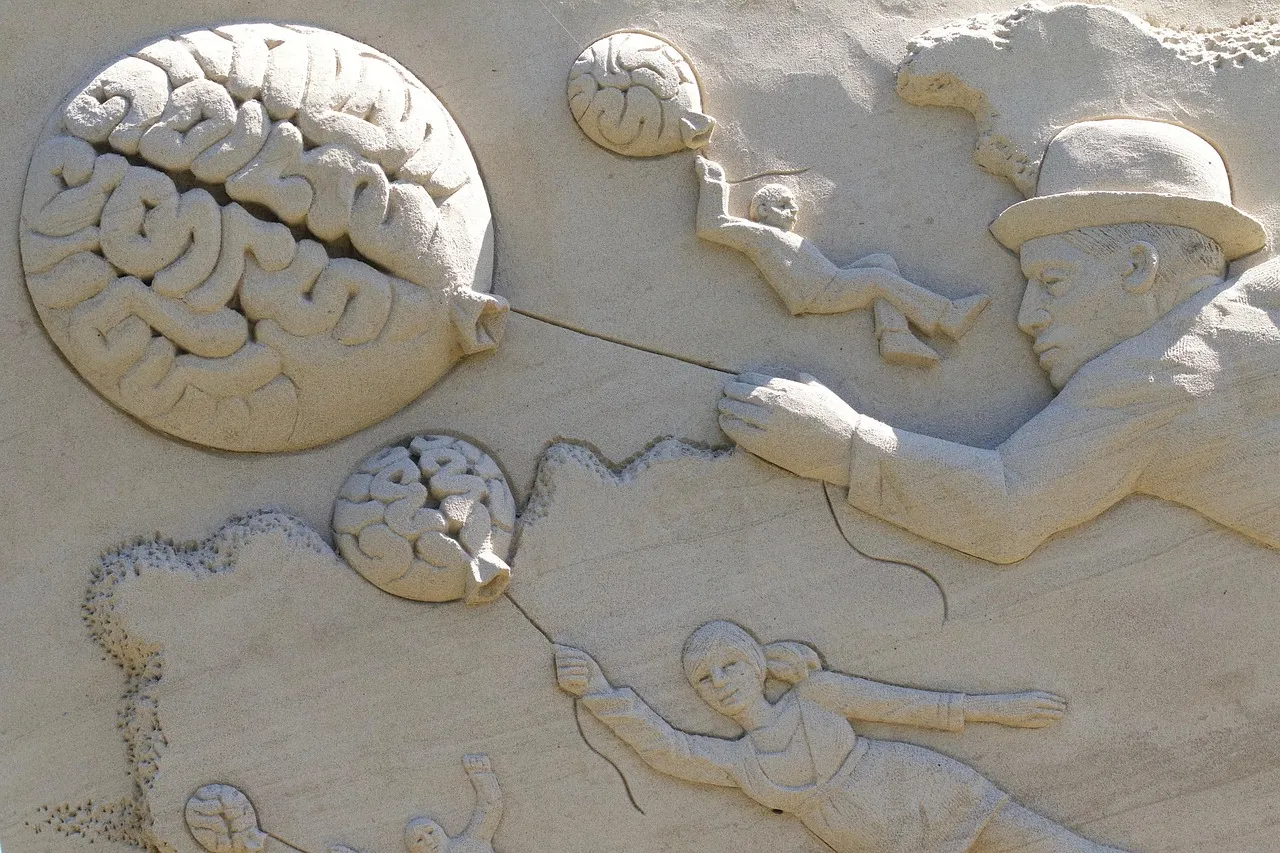 A sand relief sculpture featuring surreal imagery of a man in a bowler hat, a woman, and a child floating away like balloons shaped like human brains.